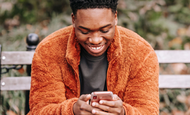 Um jovem a sorrir para o telemóvel